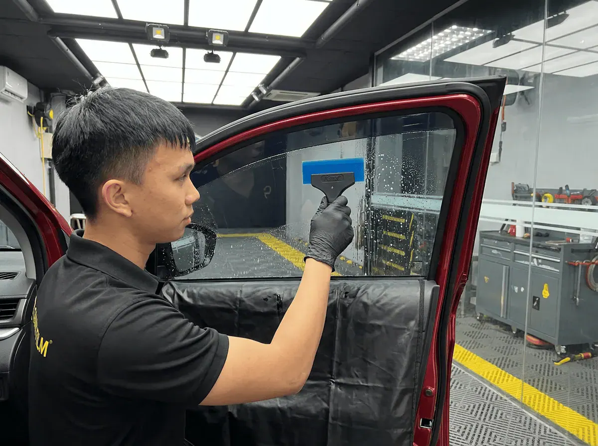 Pemasangan filem dan penyingkiran air semasa pemasangan tinted pada Perodua Alza