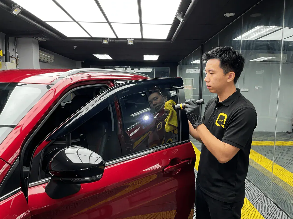 Pemeriksaan kualiti dengan lampu suluh semasa pemasangan tinted pada Perodua Alza