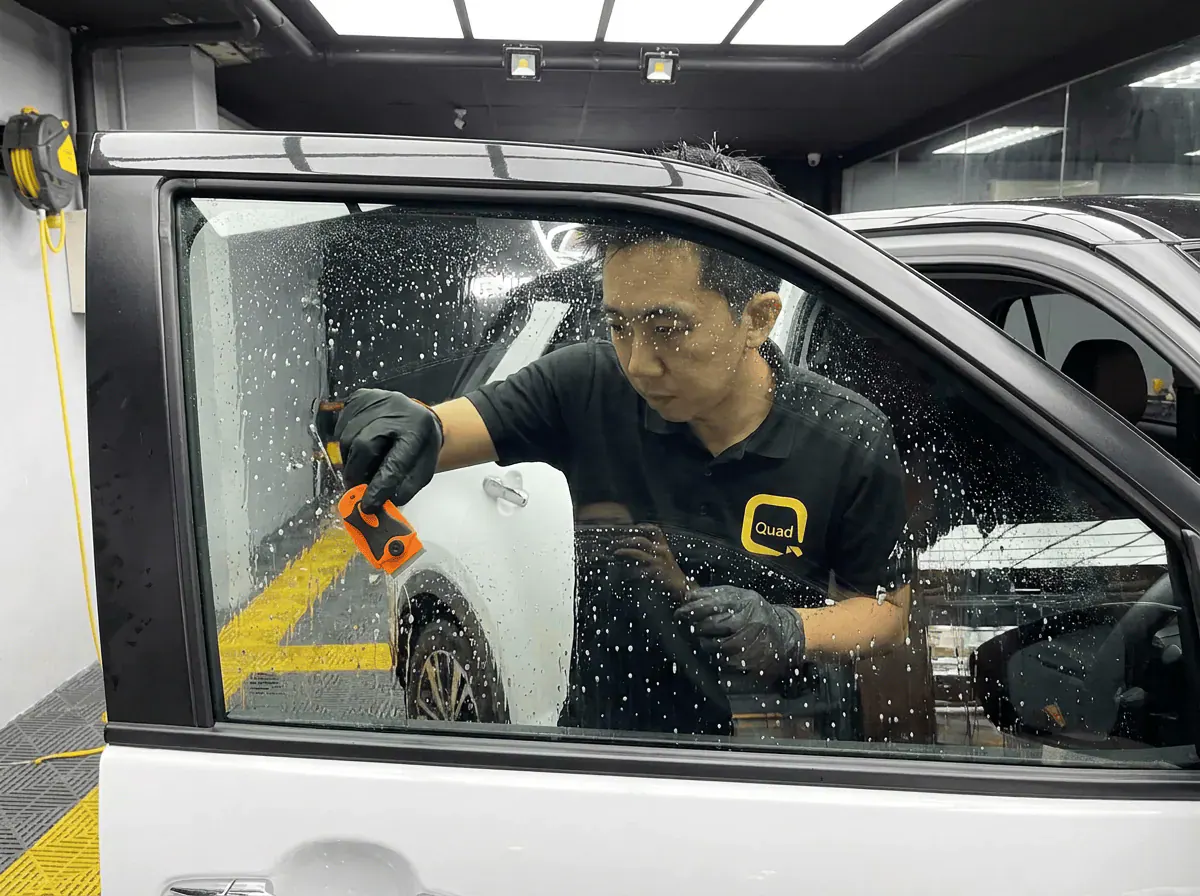Pembersihan cermin lima peringkat semasa pemasangan tinted pada Perodua Ativa