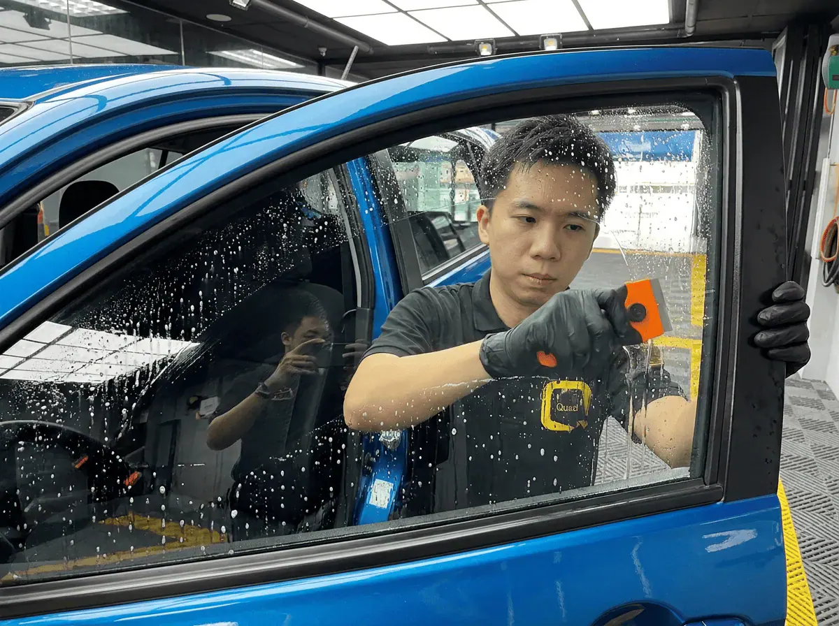 Pembersihan cermin lima peringkat semasa pemasangan tinted pada Perodua Axia