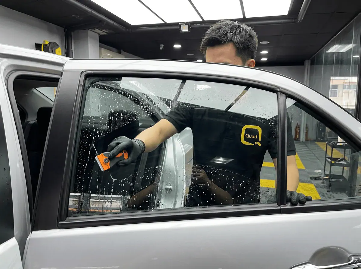 Pembersihan cermin lima peringkat semasa pemasangan tinted pada Perodua Bezza