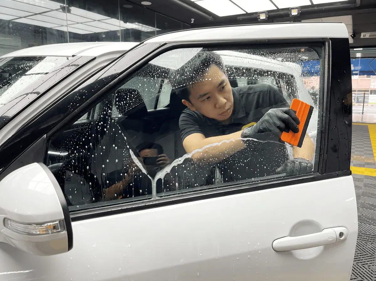 Pembersihan cermin lima peringkat semasa pemasangan tinted pada Suzuki Swift