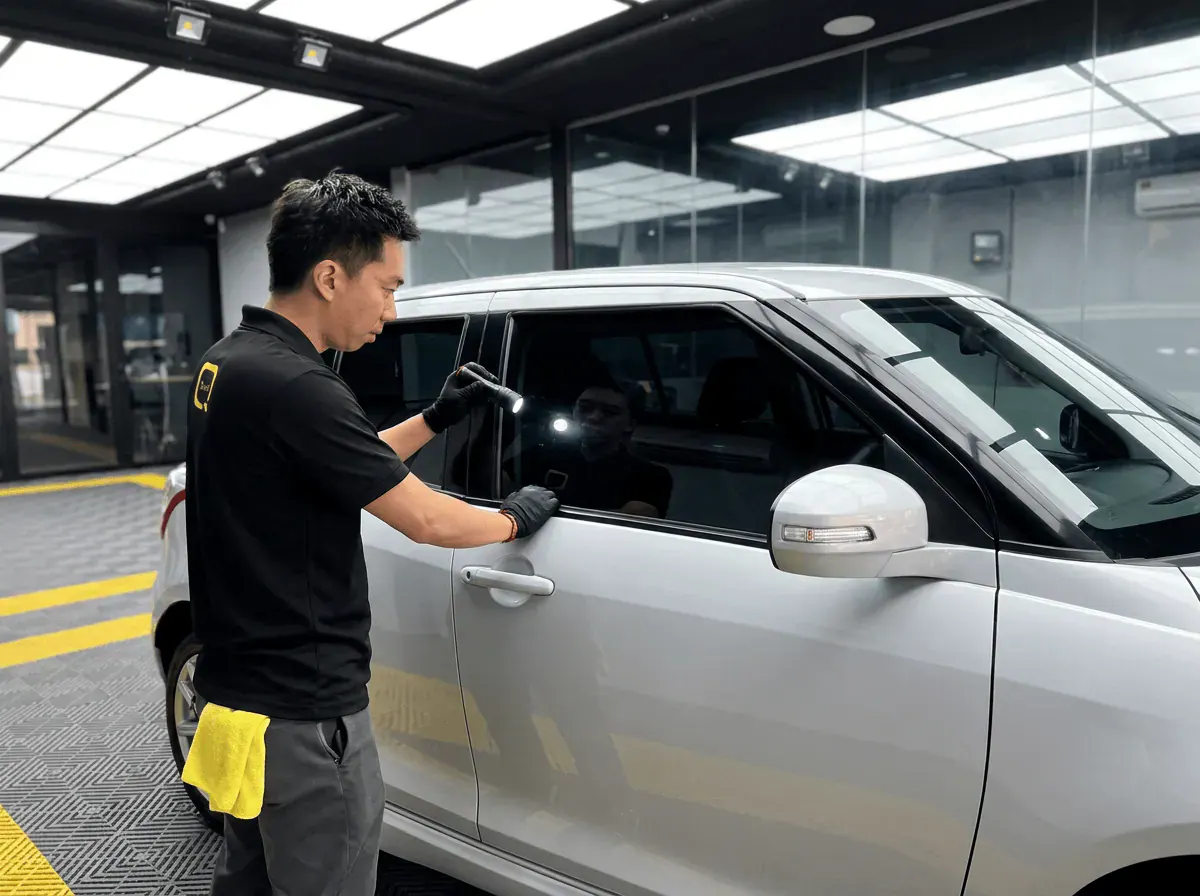 Pemeriksaan kualiti dengan lampu suluh semasa pemasangan tinted pada Suzuki Swift