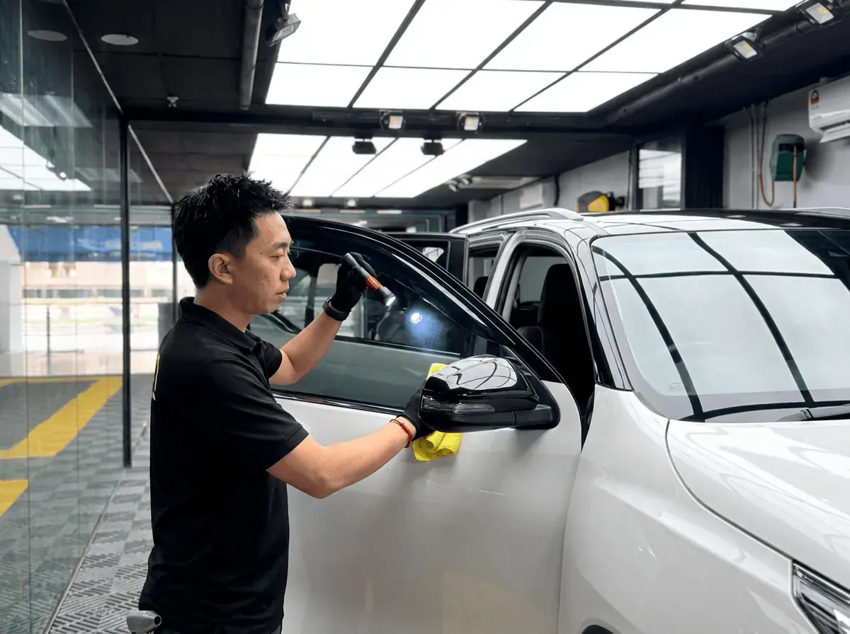 Pemeriksaan kualiti dengan lampu suluh semasa pemasangan tinted pada Toyota Fortuner