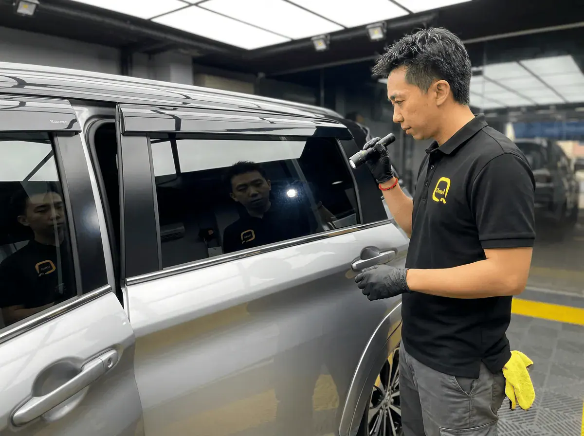 Pemeriksaan kualiti dengan lampu suluh semasa pemasangan tinted pada Toyota Veloz