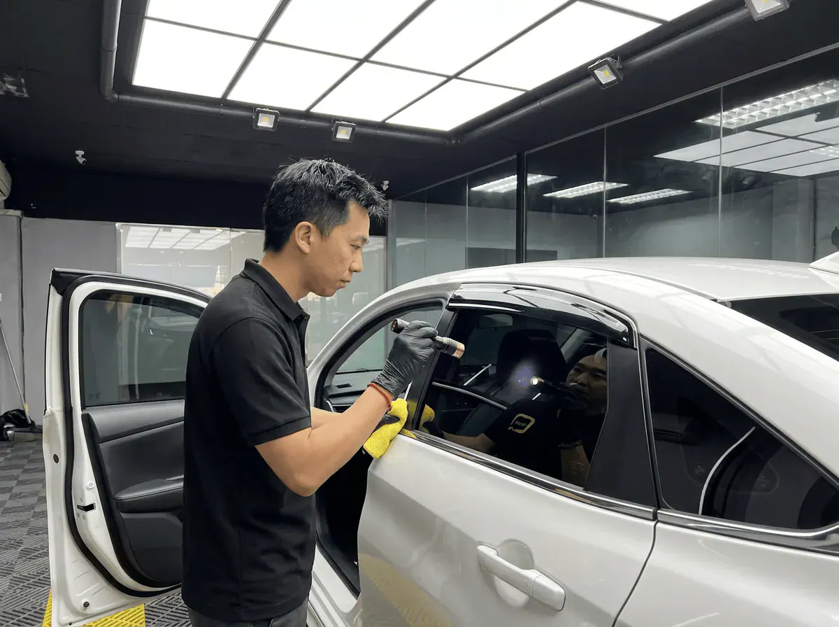 Pemeriksaan kualiti dengan lampu suluh semasa pemasangan tinted pada Toyota Vios