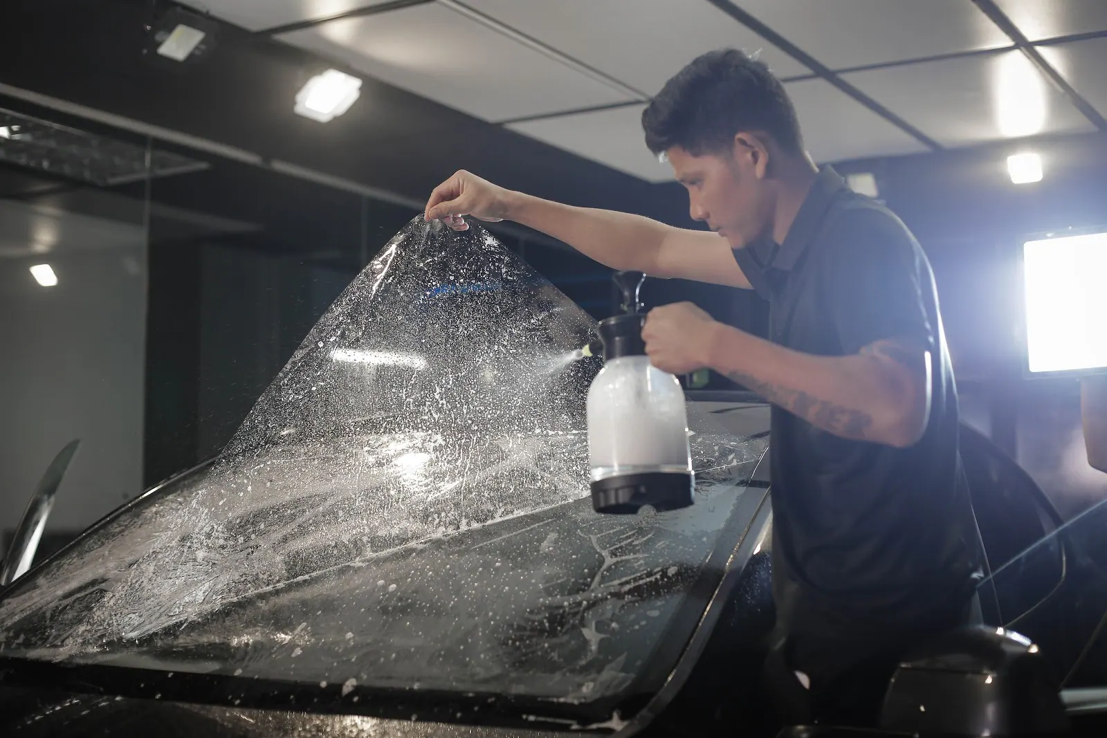 Technician wetting a sheet of window film with solution before installation