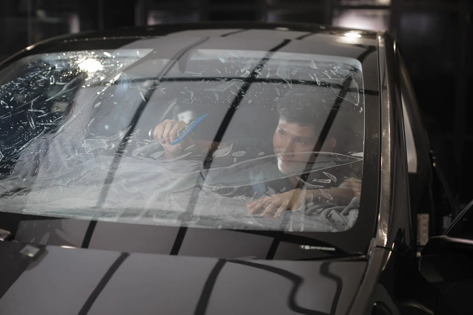 Technician aligning and smoothing tint on the inside of a front windscreen